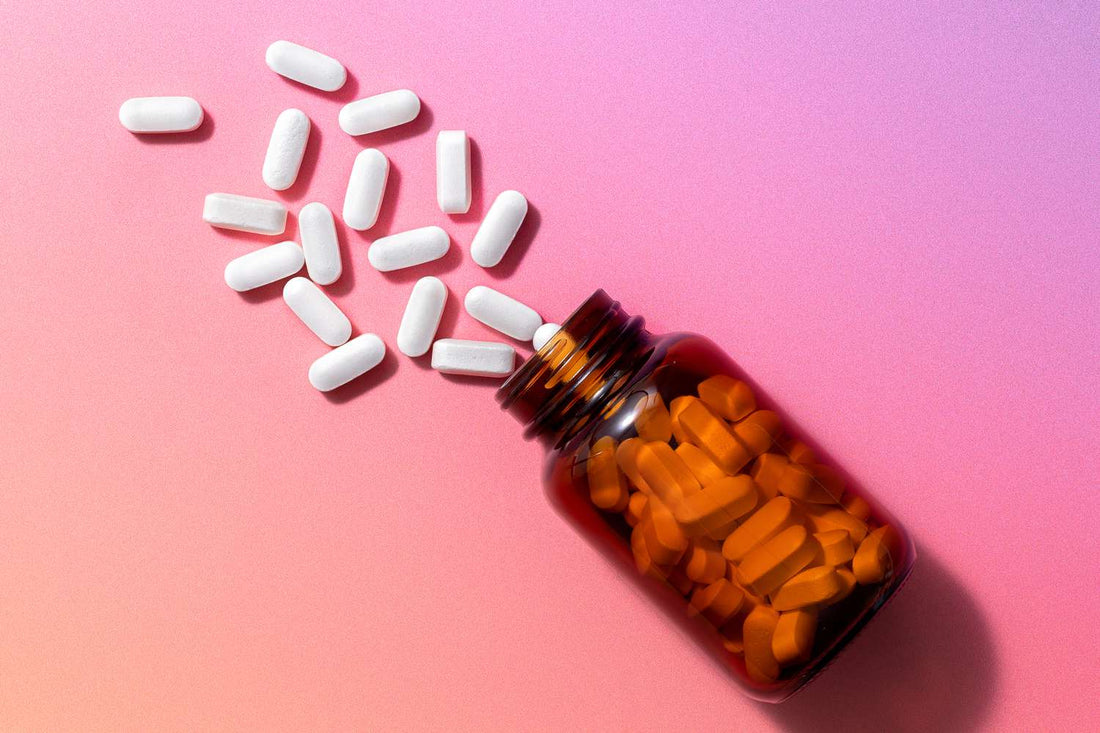 Kosttilskudskapsler og tabletter vælter ud af brun glasflaske — illustrerer vigtigheden af at vælge den rigtige form for B3-vitamin når man sammenligner NRC, NMN og NAD⁺